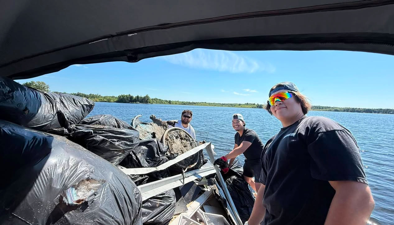 Crew loading bagged junk and scrap metal onto a boat during a lakeside junk removal job