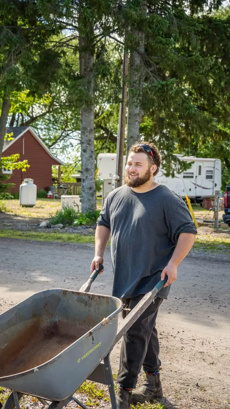 Crew member hauling a wheelbarrow of yard debris during a property cleanup